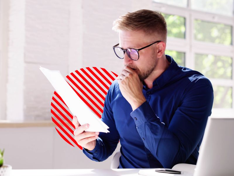 Empresário analisa documentos com expressão preocupada em um escritório iluminado. A imagem representa os desafios de emitir e conferir uma nota fiscal eletrônica com precisão e conformidade fiscal.