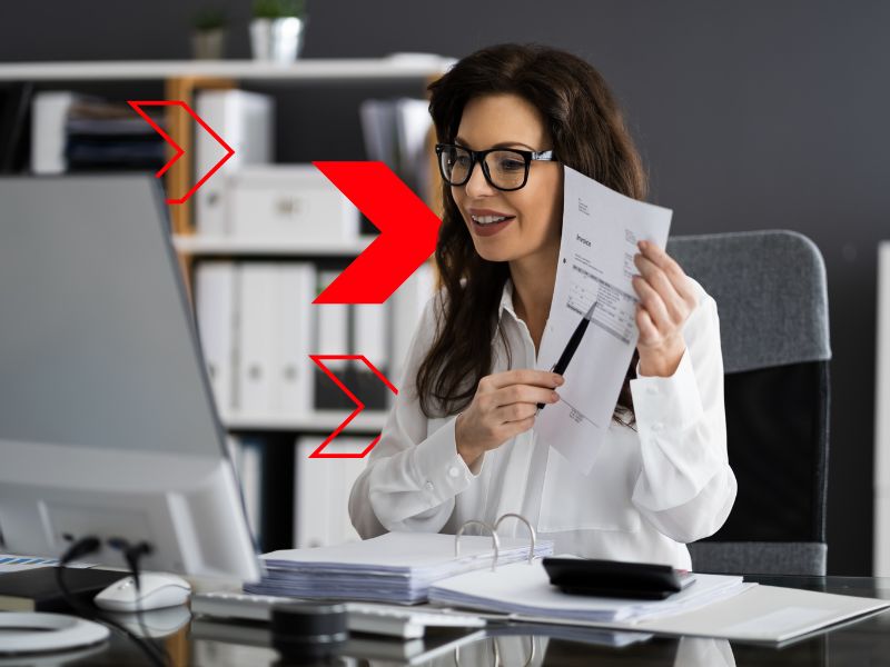 Profissional de contabilidade analisa documentos e dados em frente ao computador, representando o envio de informações e obrigações acessórias através do SPED Fiscal para garantir conformidade tributária e eficiência na gestão empresarial.