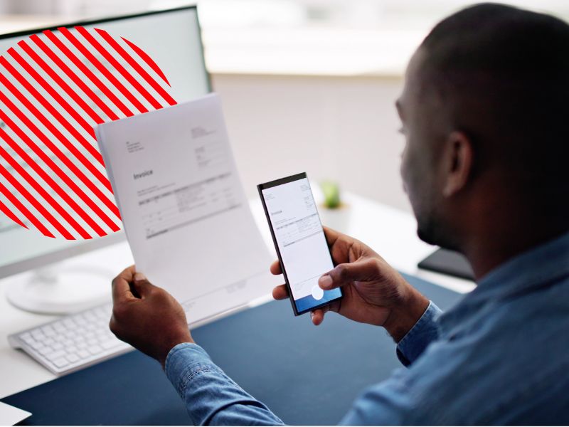 Empresário confere documentos e registra informações fiscais no celular e no computador, simbolizando o cumprimento das obrigações fiscais de forma digital e automatizada para garantir conformidade e eficiência tributária.