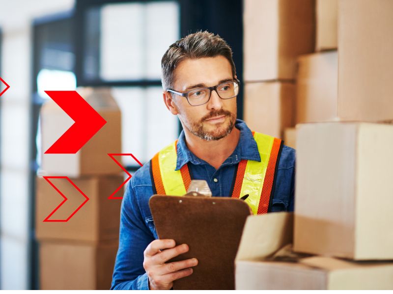 Gestor de estoque analisa pilhas de caixas com prancheta em mãos, representando a aplicação da Curva ABC para identificar produtos de maior impacto financeiro e otimizar o controle de inventário.