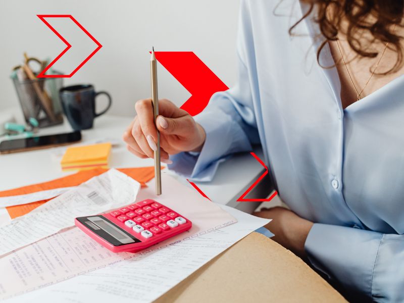 Profissional analisa documentos fiscais com calculadora e anotações sobre a mesa, representando a escolha e o enquadramento correto do regime tributário para reduzir riscos fiscais e garantir uma gestão financeira mais eficiente.