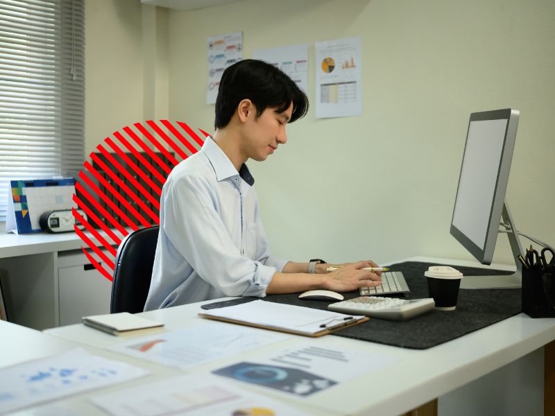 Profissional analisa dados financeiros no computador em ambiente corporativo, representando o monitoramento e a identificação de passivo fiscal para evitar riscos tributários e impactos no fluxo de caixa da empresa.
