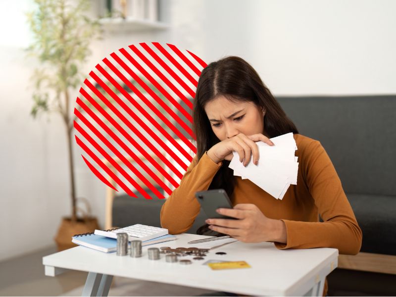 Empreendedora analisa contas e valores no celular com expressão preocupada, representando a situação em que a empresa não dá lucro por falta de controle financeiro e gestão eficiente dos custos.