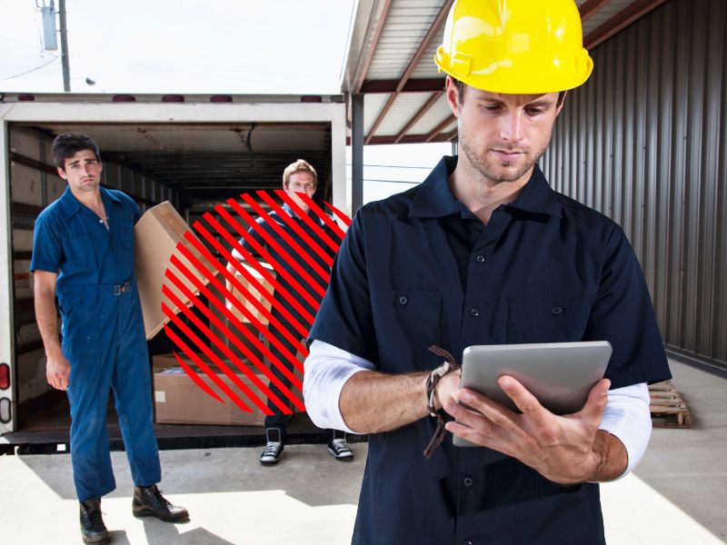 Profissional acompanha entregas por tablet enquanto equipe realiza carregamento de mercadorias, representando o controle de entregas com monitoramento em tempo real para garantir prazos, rastreabilidade e eficiência logística.