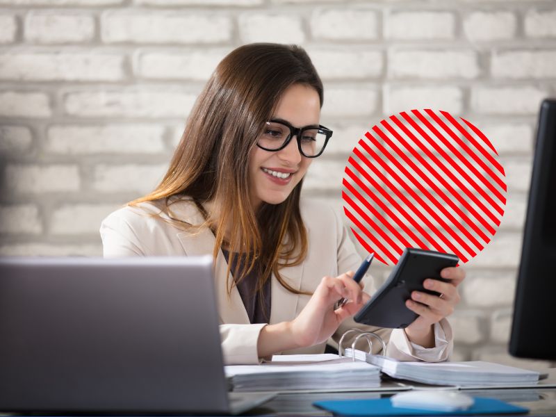 Profissional confere valores em calculadora e smartphone no escritório, representando o controle de contas a receber para acompanhar cobranças, melhorar o fluxo de caixa e manter a saúde financeira da empresa.