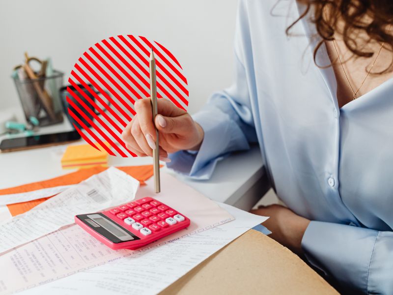 Profissional realiza cálculos financeiros com apoio de calculadora e documentos, representando a análise da margem de contribuição para identificar a rentabilidade dos produtos, apoiar a formação de preços e melhorar o controle financeiro empresarial.