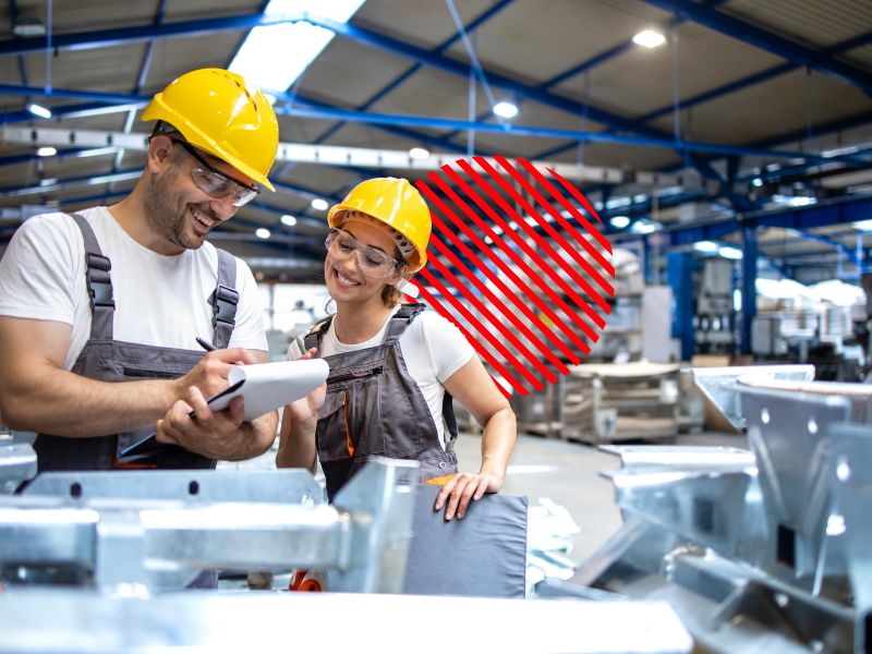 Profissionais analisam informações na área de produção utilizando tablet, representando a identificação de gargalos operacionais para eliminar atrasos, otimizar processos e aumentar a eficiência operacional da empresa.