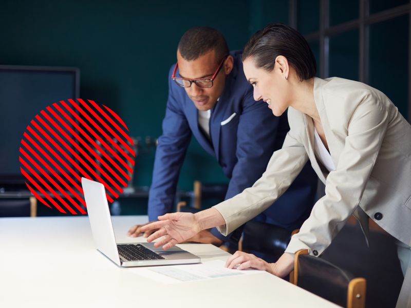 Profissionais analisando informações em um notebook, representando um ERP integrado que conecta setores, centraliza dados e melhora a tomada de decisão empresarial.