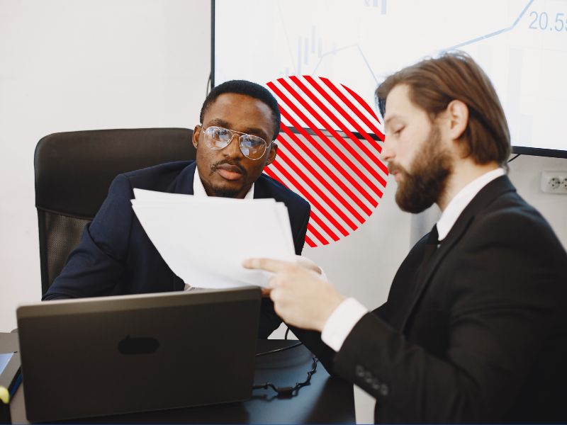 Gestores analisando documentos durante reunião, representando a segregação de funções para fortalecer os controles internos, reduzir riscos operacionais e garantir maior segurança na gestão empresarial.
