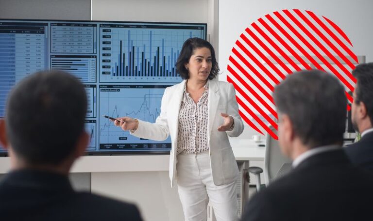 Profissional apresenta gráficos financeiros em tela para uma equipe durante reunião sobre ajuste a valor presente.