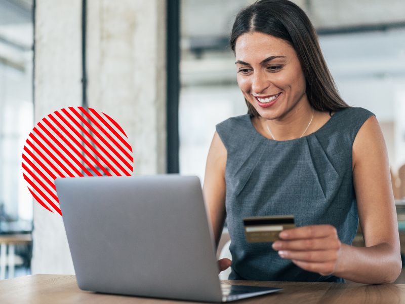 Mulher sorrindo segurando cartão de crédito ao lado do notebook, representando os prazos de pagamento e recebimento do ciclo de conversão de caixa